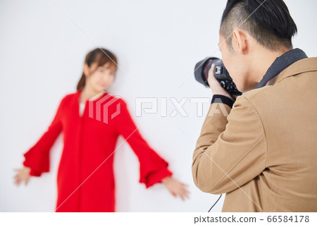 Young female model in red coat and photographer 66584178