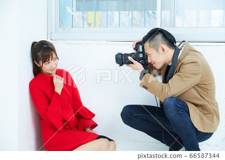 Young female model in red coat and photographer Young female model in red coat and photographer 66587344