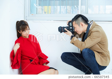 Young female model in red coat and photographer 66587345