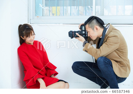 Young female model in red coat and photographer 66587346