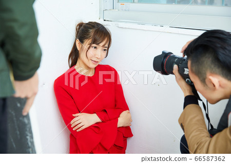 Young female model in red coat and photographer Young female model in red coat and photographer 66587362