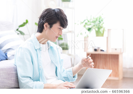 Young men enjoying online shopping while looking at a computer Young men enjoying online shopping while looking at a computer 66596366