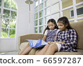 Little student girls enjoy reading book on sofa at 66597287