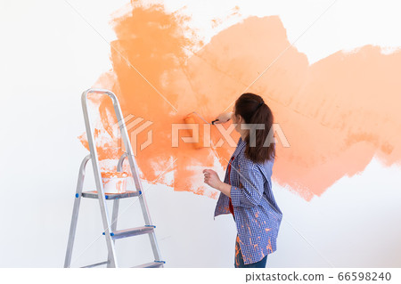 Pretty young woman with painting roller indoors. Redecoration, renovation, apartment repair and refreshment concept. 66598240