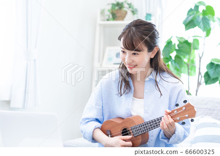Young woman taking a lesson of musical instrument (ukulele) online Young woman taking a lesson of musical instrument (ukulele) online 66600325
