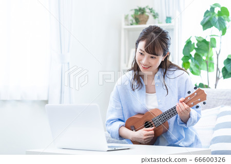 Young woman taking a lesson of musical instrument (ukulele) online Young woman taking a lesson of musical instrument (ukulele) online 66600326