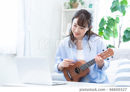 Young woman taking a lesson of musical instrument (ukulele) online 66600327