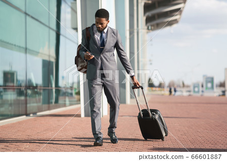 African Entrepreneur Using Phone Walking With Travel Suitcase At Airport 66601887