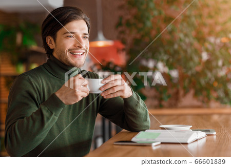 Enthusiastic guy freelancer having coffee break at cafe 66601889
