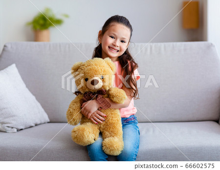 Chinese Girl Hugging Teddy Bear Sitting On Couch At Home Chinese Girl Hugging Teddy Bear Sitting On Couch At Home 66602575