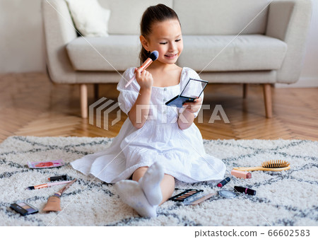 Adorable Asian Girl Making Makeup Playing Sitting On Floor Indoors Adorable Asian Girl Making Makeup Playing Sitting On Floor Indoors 66602583