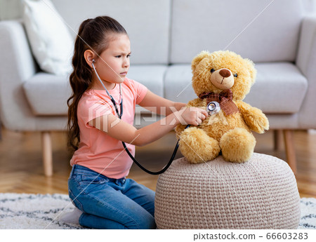 Asian Girl Playing Doctor Treating Teddy Bear Toy At Home 66603283