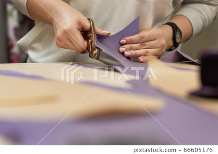 female hand with the scissors cutting fabric. 66605176