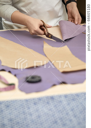 female hand with the scissors cutting fabric. female hand with the scissors cutting fabric. 66605180