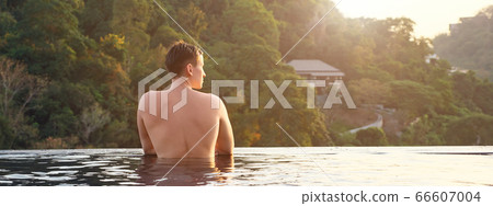 man in hotel outdoor swimming pool looking at pictorial tropical forestry hilly landscape 66607004