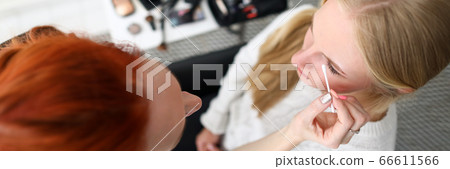 Female makeup artist corrects model eye makeup Female makeup artist corrects model eye makeup 66611566