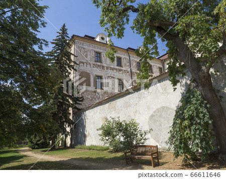Renaissance style castle with Sgraffito decorated facade, park, footpath, green trees garden and wooden bench, sunny summer day 66611646