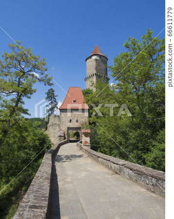 medieval castle Zvikov (Klingenberg) main entry gate with round tower and stone bridge, green trees and blue sky, castle is placed at confluence of the Vltava and Otava rivers, South Bohemian Region 66611779