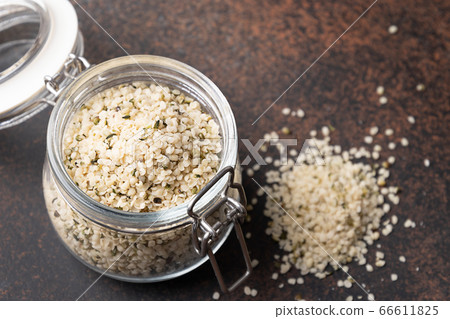 Hemp kernels in glass jar on brown. Close up Hemp kernels in glass jar on brown. Close up 66611825