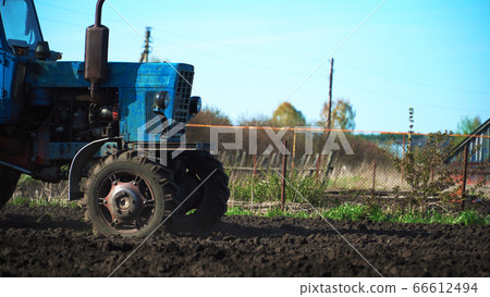 The tractor cultivates and cuts furrows in the The tractor cultivates and cuts furrows in the 66612494