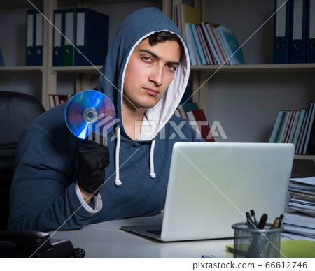 Young hacker hacking into computer at night 66612746