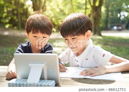 A boy studying outdoors while looking at the screen A boy studying outdoors while looking at the screen 66612751