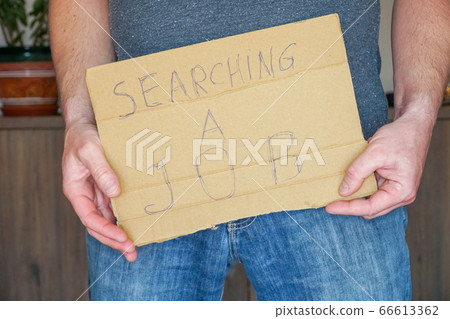 Man in jeans holds a cardboard in his hands search a job Man in jeans holds a cardboard in his hands search a job 66613362