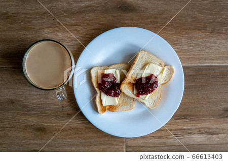 Cup of coffe with milk and two slices of toasted sandwich Bread with Butter and Raspberry. Breakfast with coffee. Side view. Free space for text. Cup of coffe with milk and two slices of toasted sandwich Bread with Butter and Raspberry. Breakfast with coffee. Side view. Free space for text. 66613403