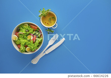 Fresh green vegetable salad with lettuce, tomatoes and cucumber in bowl on blue background with white knife and fork, healthy eating and dieting concept, top view with copy space Fresh green vegetable salad with lettuce, tomatoes and cucumber in bowl on blue background with white knife and fork, healthy eating and dieting concept, top view with copy space 66614226
