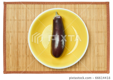 violet eggplant on a yellow plate on a cane place 66614418