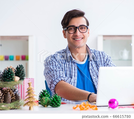Young man making christmas decoration from cones Young man making christmas decoration from cones 66615780