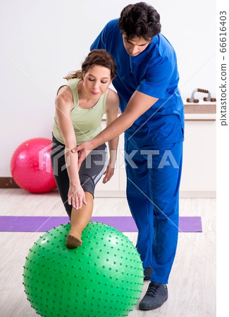 Fitness instructor helping sportsman during exercise 66616403