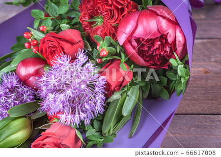 bouquet with red flowers in purple packaging on wooden background. high quality 66617008