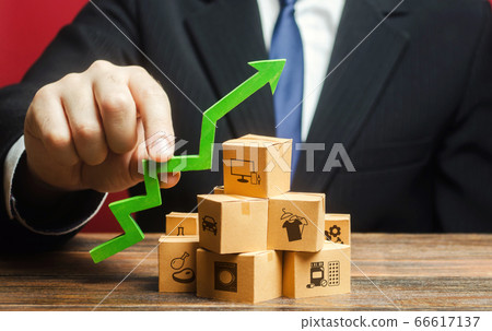 Businessman holding a green arrow up over boxes. Tactics and strategy, marketing. Value added goods. Boost sales rate. Increasing production of goods, expanding export opportunities, finding markets. 66617137