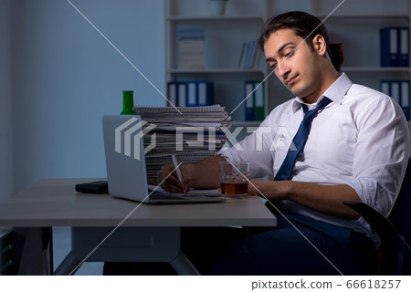 Alcohol addicted businessman working late in the office Alcohol addicted businessman working late in the office 66618257