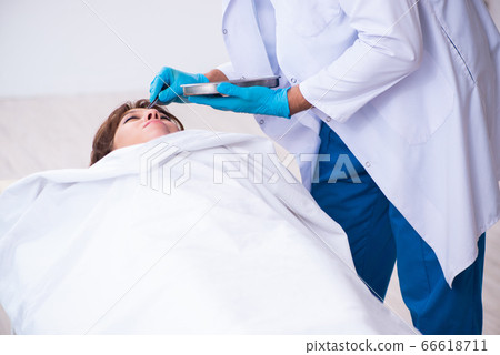 Police coroner examining dead body corpse in morgue 66618711