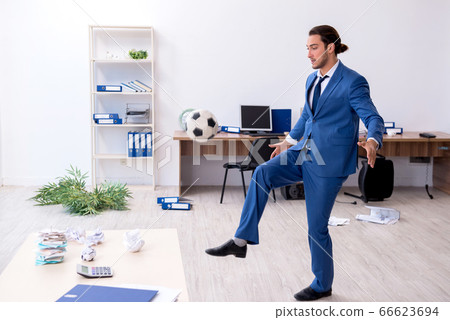 Young male employee playing football in the office 66623694