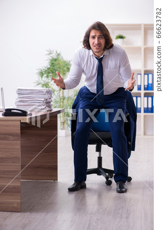 Young male employee unhappy with excessive work Young male employee unhappy with excessive work 66623782