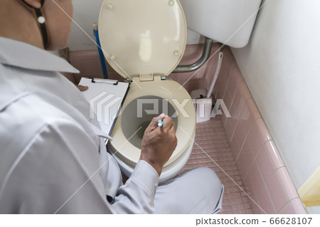 A businessman investigating an old-fashioned flush toilet before housing renovation A businessman investigating an old-fashioned flush toilet before housing renovation 66628107
