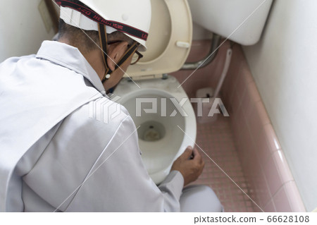 A businessman investigating an old-fashioned flush toilet before housing renovation A businessman investigating an old-fashioned flush toilet before housing renovation 66628108
