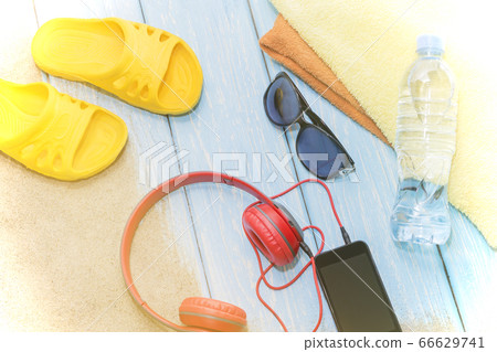 Bottle of water and bright towels, yellow slate on blue background and sunglasses. Copy Space. 66629741