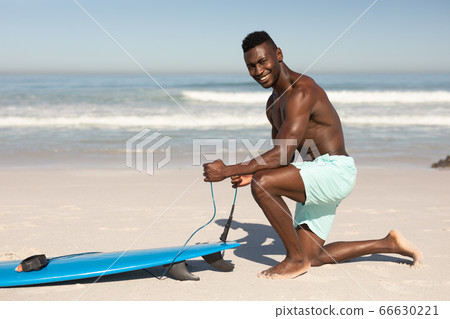 African American man and surf board on the beach 66630221