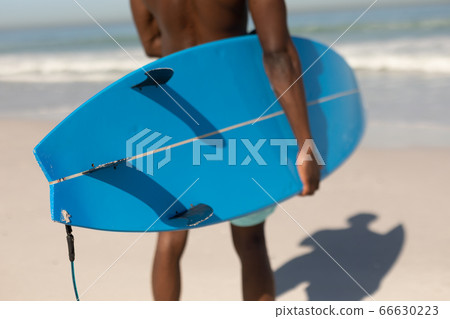 African American man holding surf board on the beach African American man holding surf board on the beach 66630223