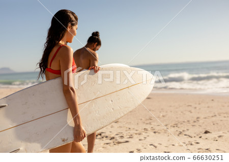 Young mixed race people holding surf boards on beach Young mixed race people holding surf boards on beach 66630251