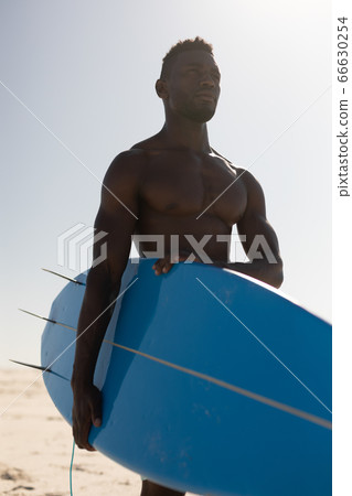 African American man holding surf board on the beach African American man holding surf board on the beach 66630254