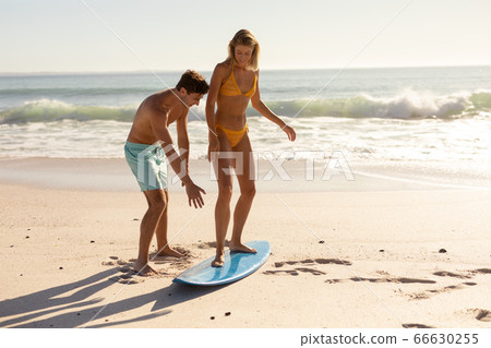 Young caucasian people practising surf on beach Young caucasian people practising surf on beach 66630255