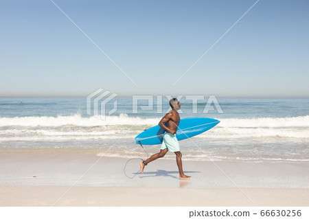 African American man holding surf board on the beach African American man holding surf board on the beach 66630256
