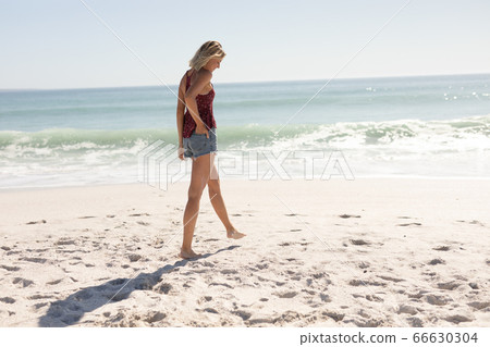 Young Caucasian woman walking on the beach Young Caucasian woman walking on the beach 66630304