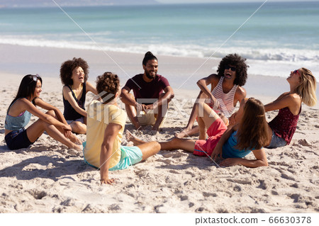 Multi-ethnic group of male and female sitting on the beach 66630378