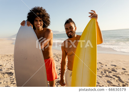 Young mixed race men holding surf boards on beach 66630379